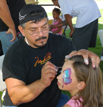 Mark Reid painting a butterfly mask on a young girl